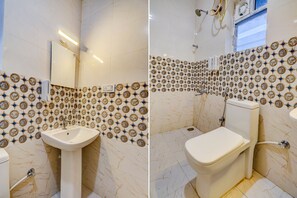 A bathroom with a sink, toilet, and a mirror. The walls are tiled with a patterned design.