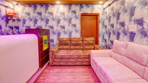A hotel room with a patterned wall, a wooden door, a sofa, and a reception desk. - Fabhotel Kings Suites (Bengaluru)