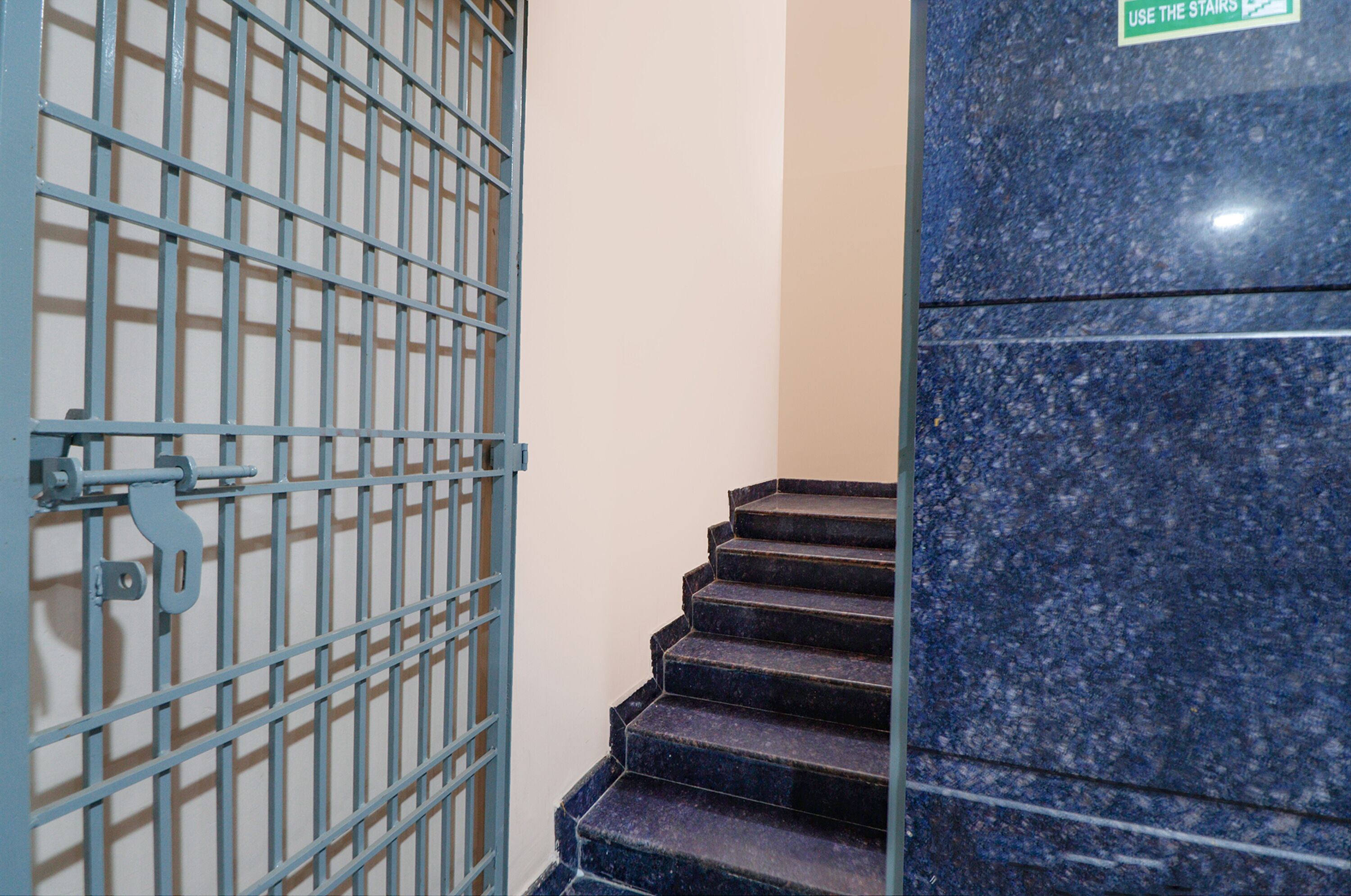 A set of dark granite stairs with a sign indicating to use the stairs.