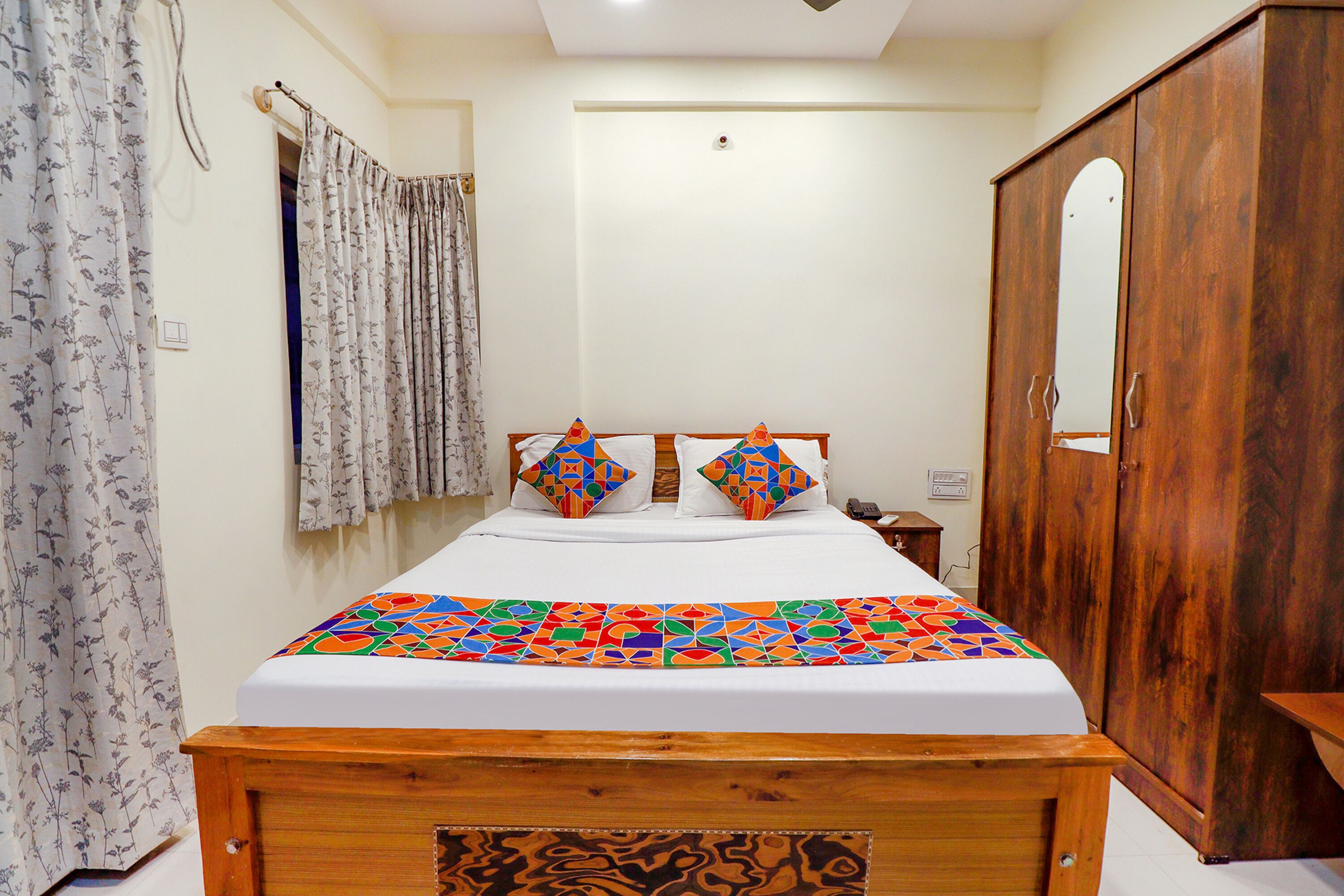 A bedroom with a bed, wooden wardrobe, and a bathroom with a shower curtain.