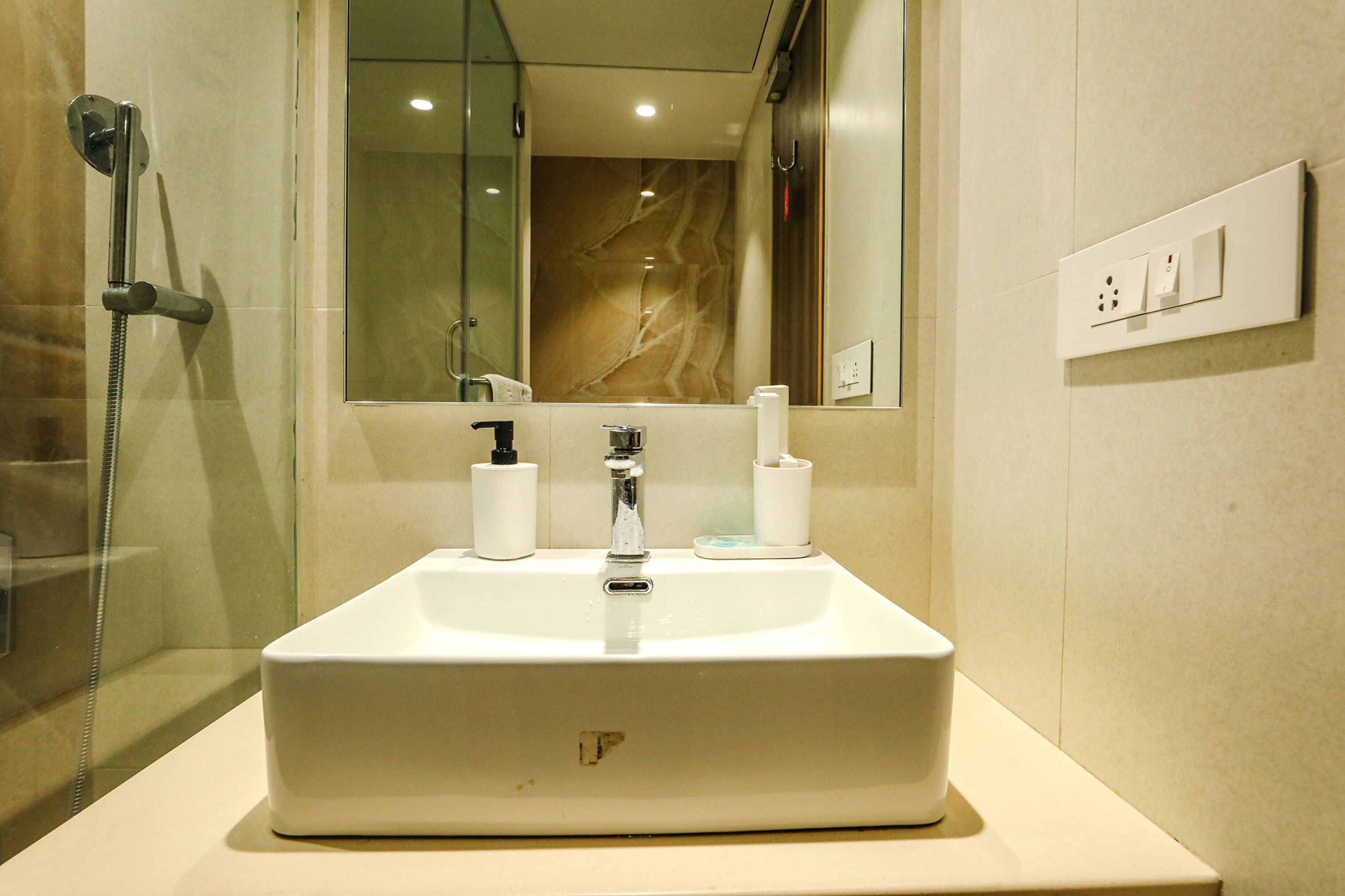 Un bagno con un lavandino bianco, uno specchio e una doccia.