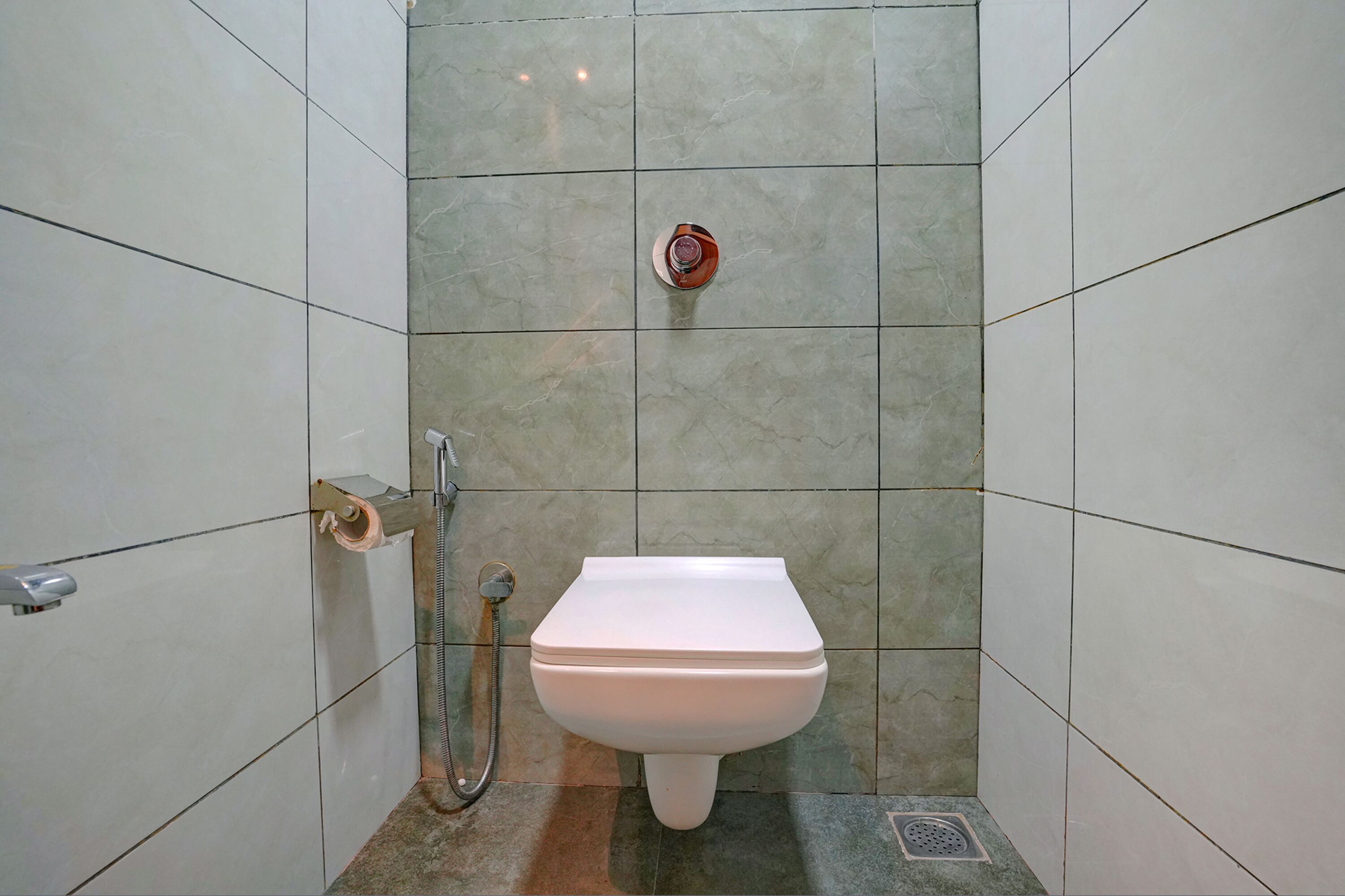 Um banheiro pequeno revestido com azulejos, com vaso sanitário, chuveiro e secador de mãos.