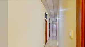 A long, narrow hallway with a marble floor, wooden doors, and recessed lighting. - Fabexpress Colaba Grand (Mumbai)