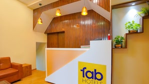 A reception desk with a 'fab hotels' logo, wooden paneling, and pendant lighting. - Fabexpress Colaba Grand (Mumbai)