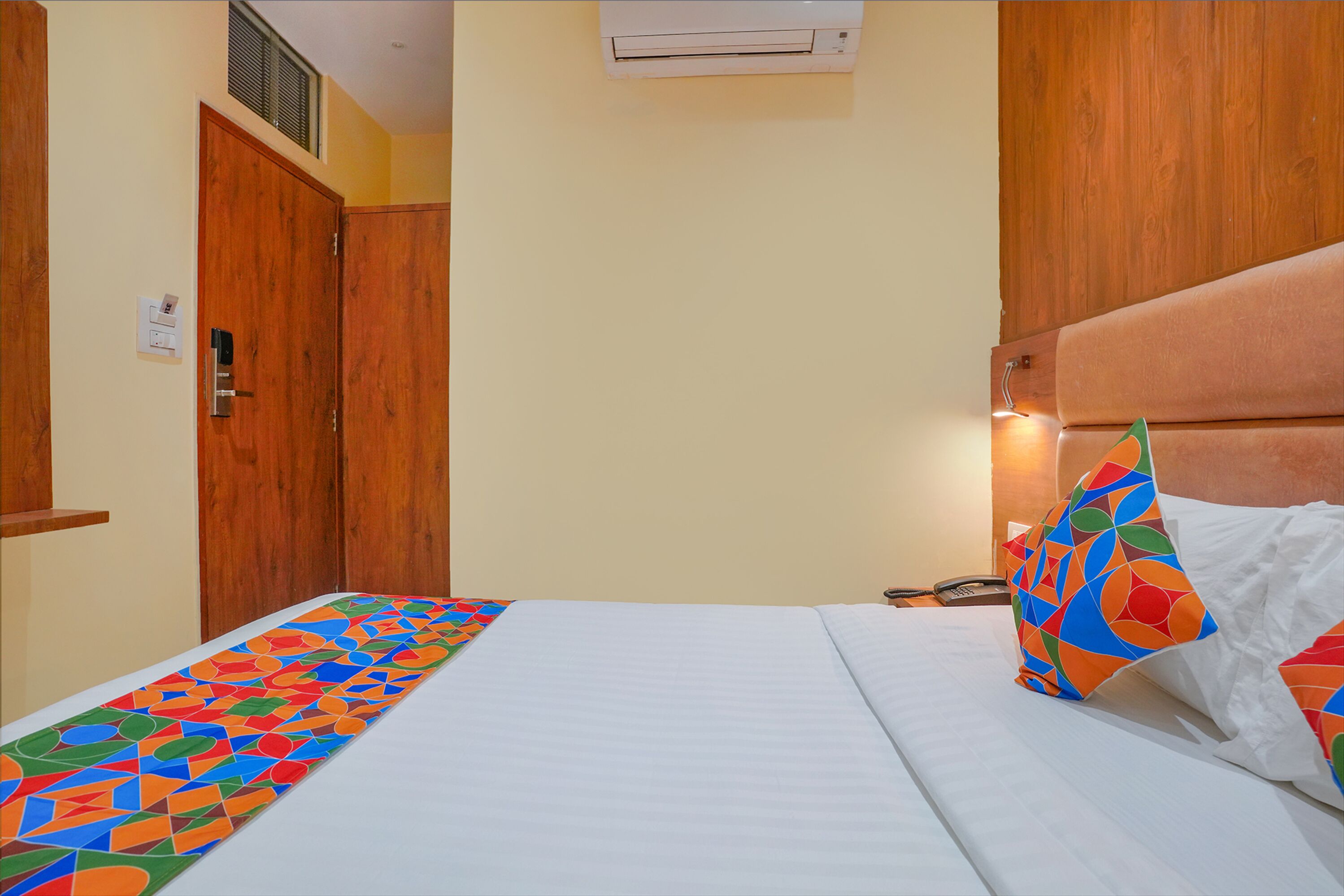 Une chambre d’hôtel comprenant un lit, une armoire en bois, un climatiseur fixé au mur et un téléphone.