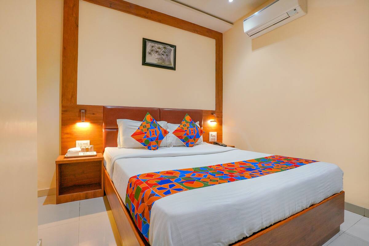 A neatly made bed with a colorful geometric-patterned bedspread, a wooden headboard, and bedside lamps.