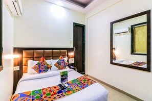Une chambre d’hôtel équipée d’un lit, d’une tête de lit, d’un miroir et d’un appareil de climatisation.