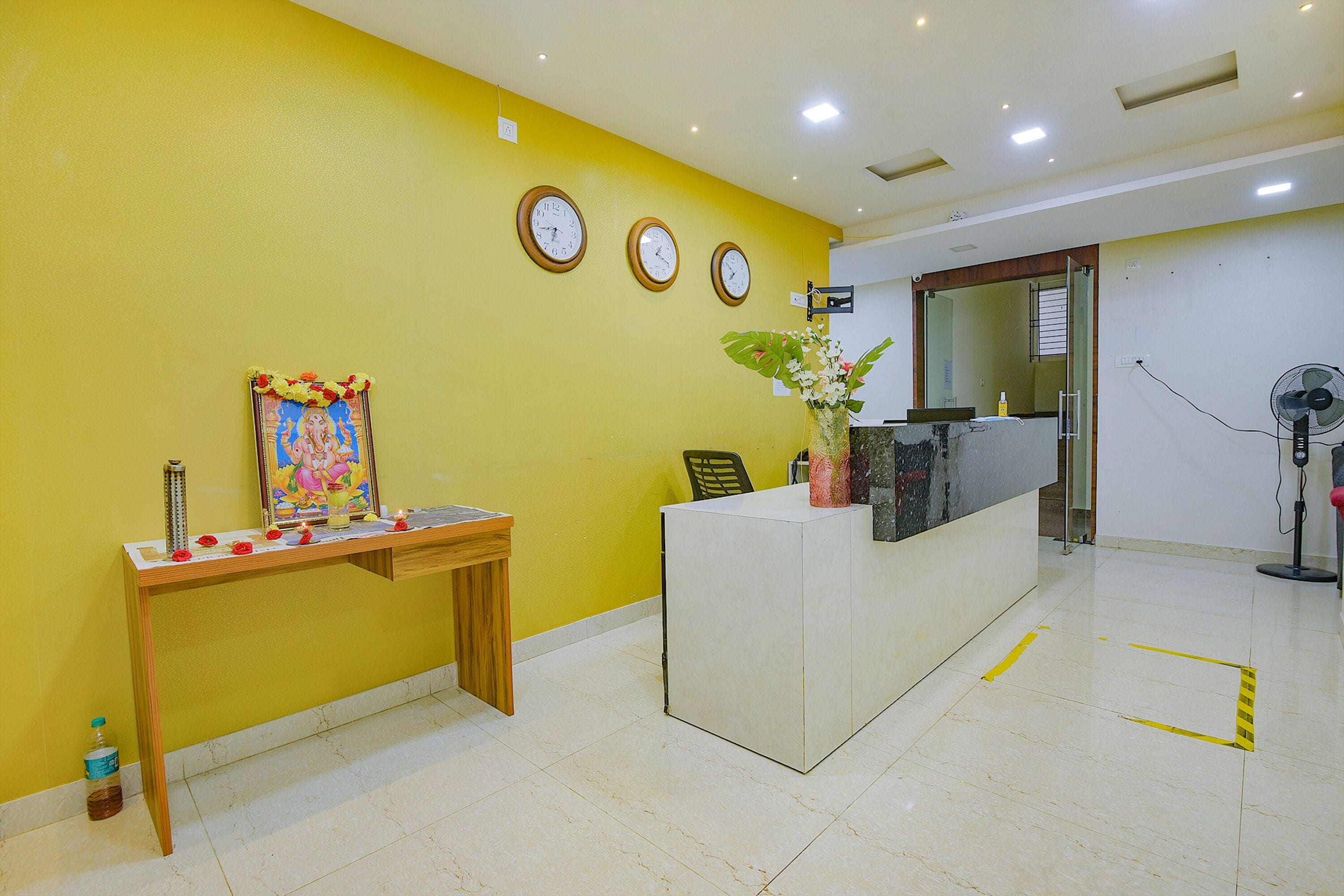 A reception area with a desk, a small statue, a framed picture, and a potted plant.