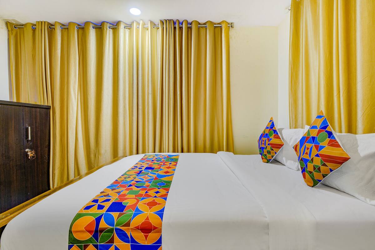 A hotel room with a bed, a wardrobe, and curtains.