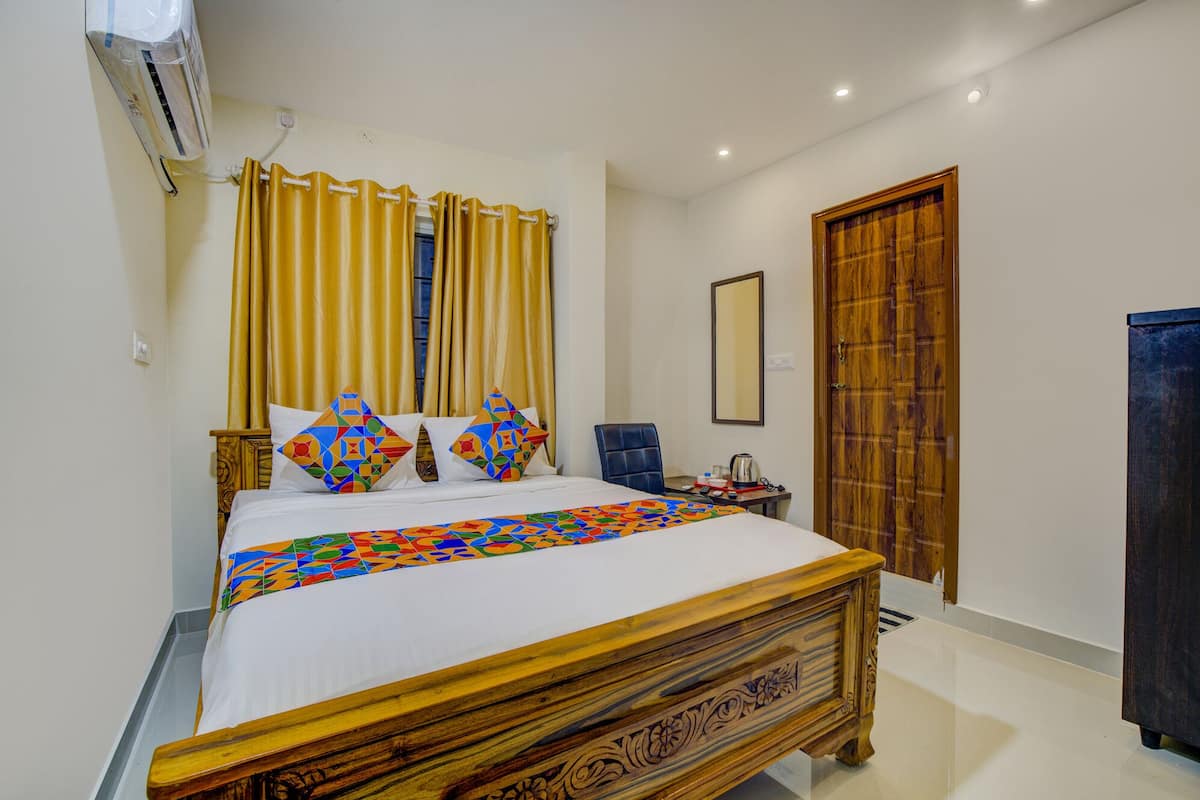 A neatly arranged bedroom with a wooden bed, a small table with a kettle, and a mirror on the wall.