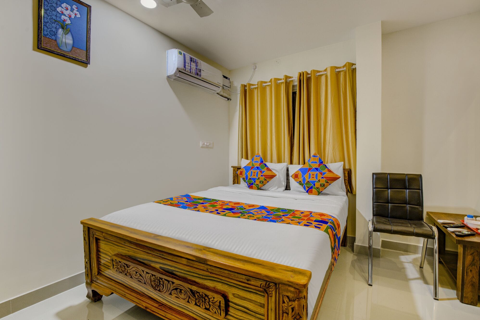 A hotel room with a wooden bed, a bedside table, a chair, and a wall-mounted air conditioner.