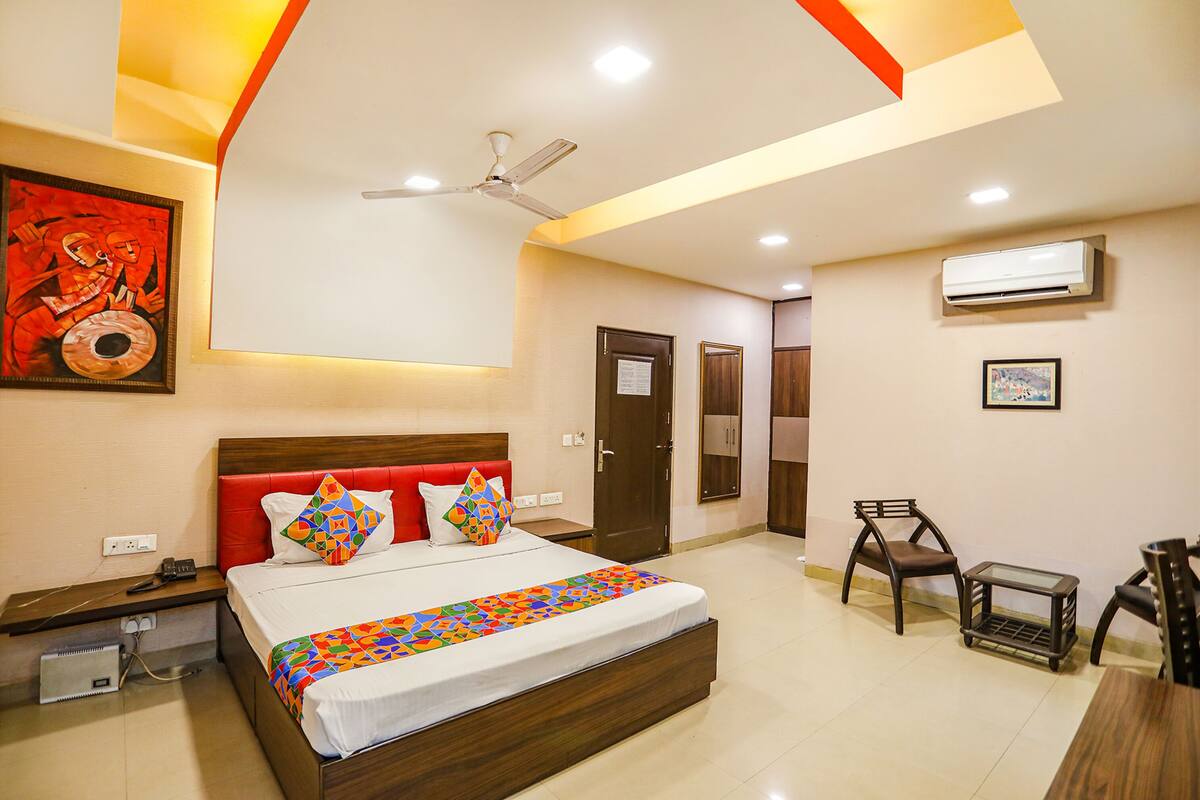 A modern hotel room with a large bed, a ceiling fan, and a small table with chairs.