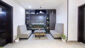 A modern living room with a sofa set, a coffee table, and a fish tank. - Itsy Hotels NV, Sushant Lok (Gurugram)