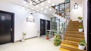 A modern interior with a staircase, potted plants, and a ceiling with hanging lights. - Itsy Hotels NV, Sushant Lok (Gurugram)