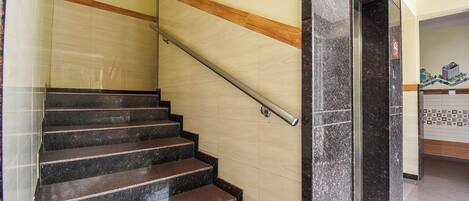 A staircase with a handrail, beige walls, and a wooden trim.