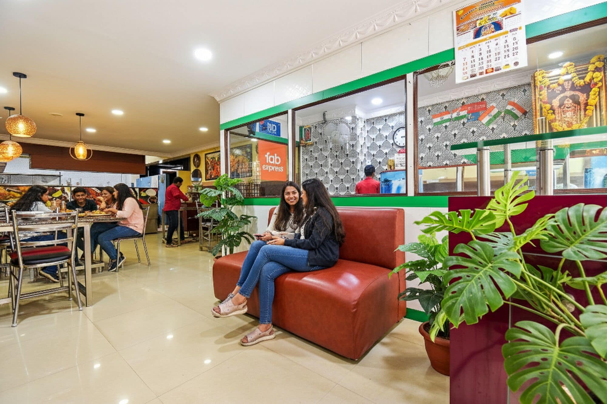 A restaurant interior with a seating area, a counter, and a wall with a calendar and decorative elements.