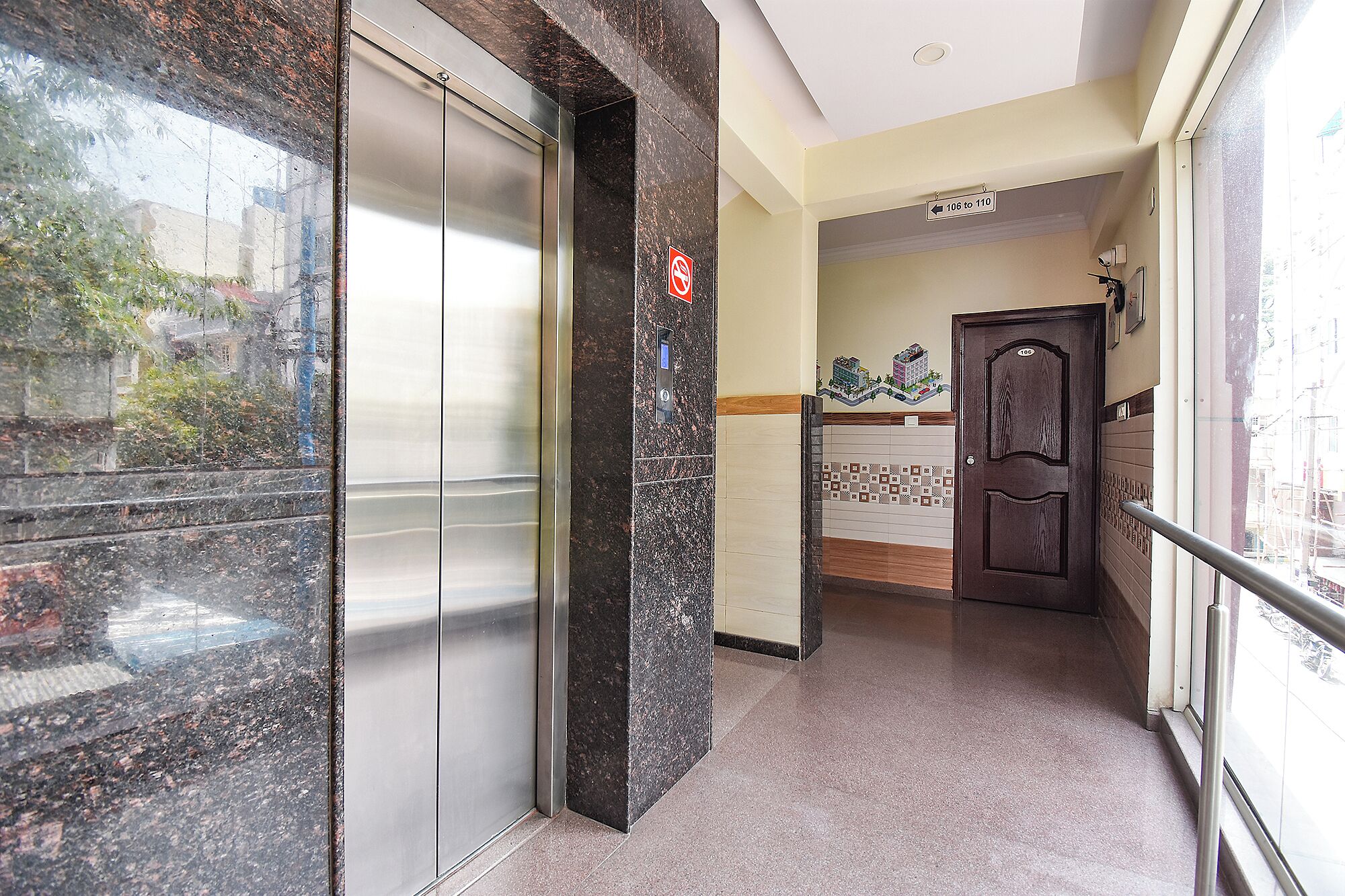 A hallway with a marble floor, a door with a number plate, and an elevator.