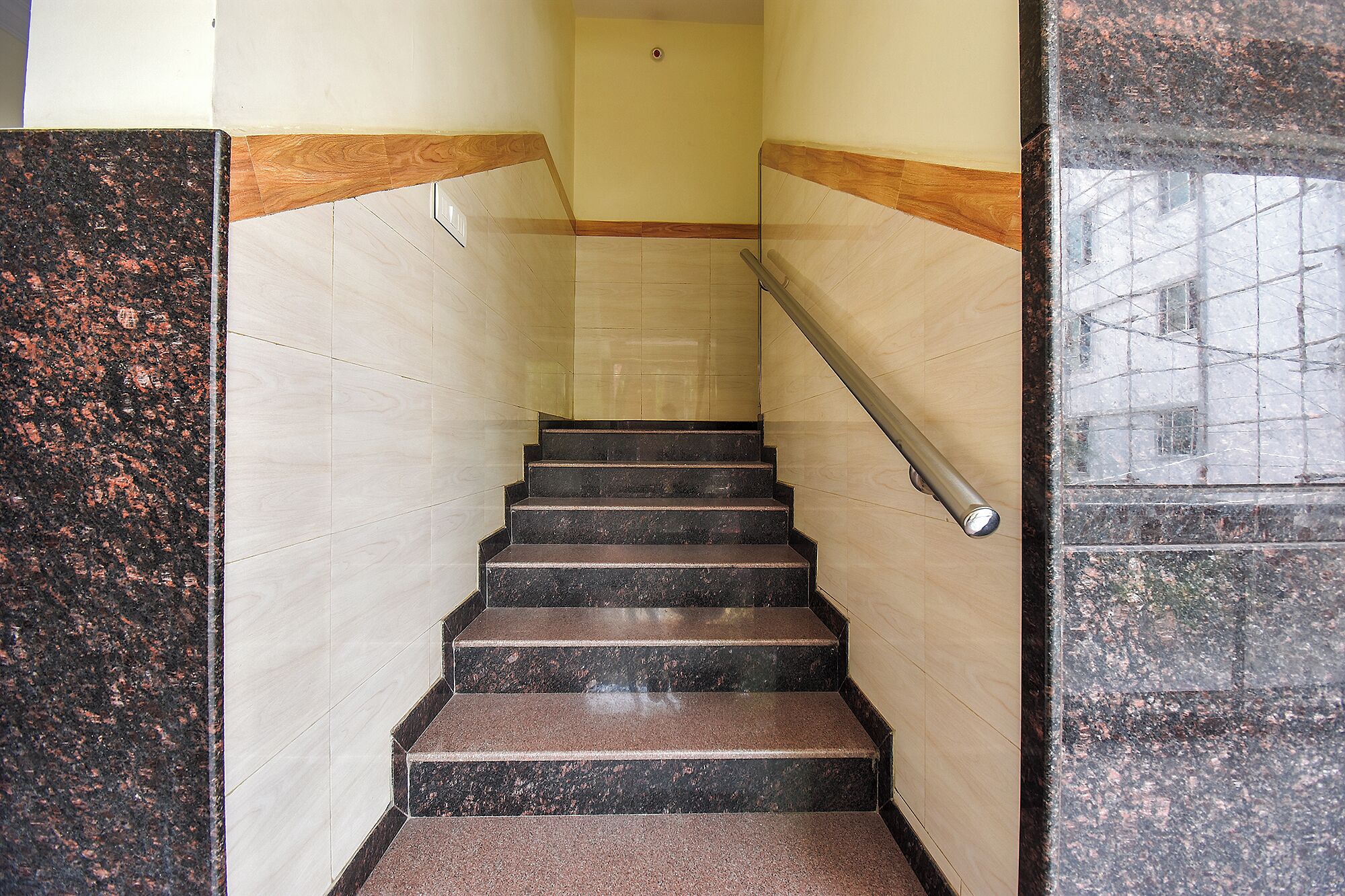 A staircase with black steps and beige walls, leading to a door at the top.