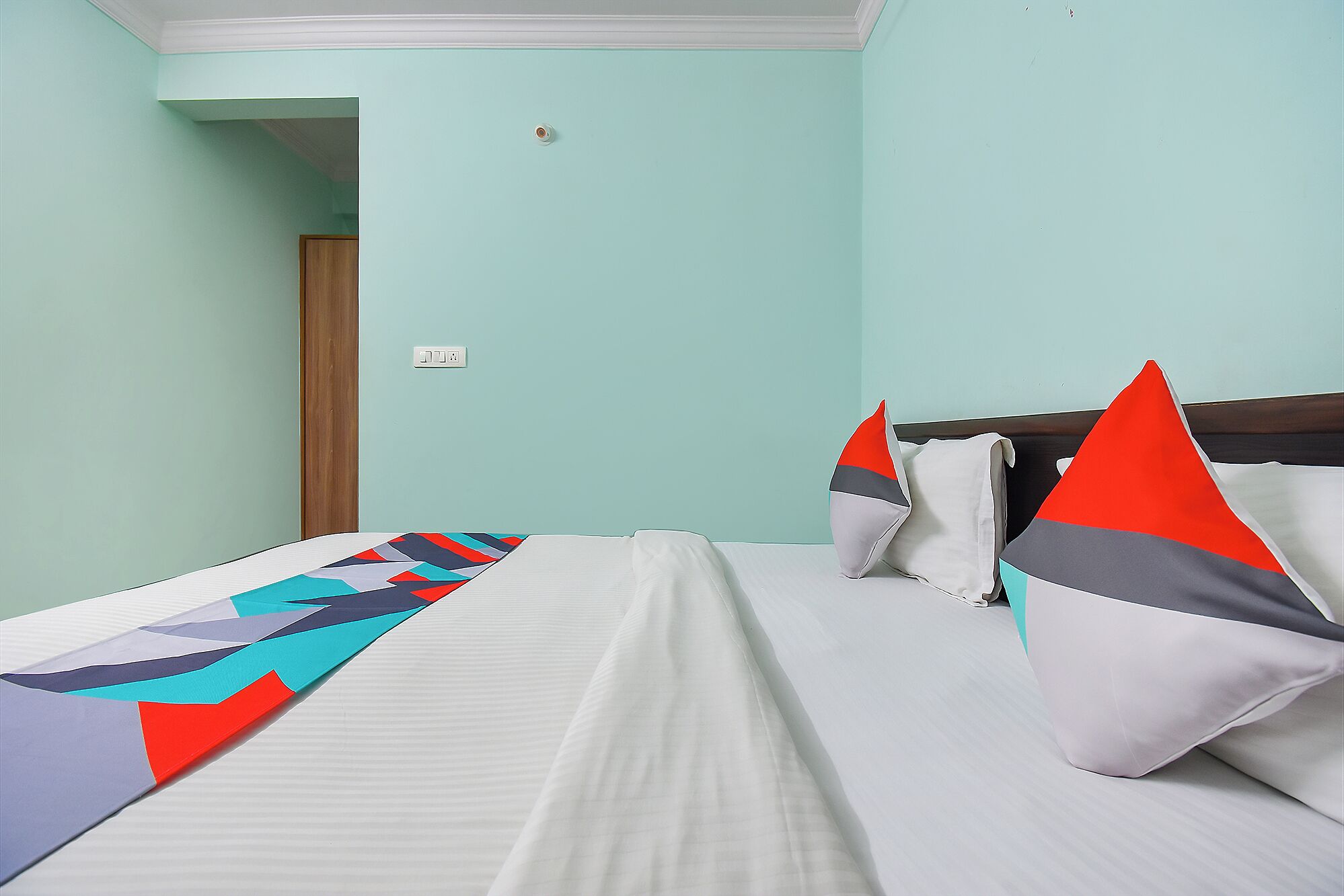 A hotel room with a bed, pillows, and a blanket.