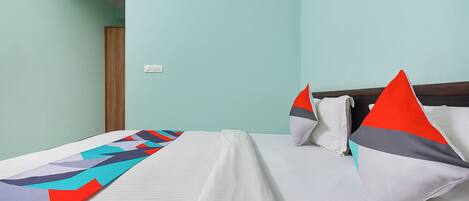 A hotel room with a bed, pillows, and a blanket.