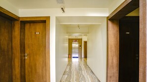 A hotel corridor with wooden doors numbered 205 and 202, leading to an elevator. - Fabhotel Happy Homely Stay (Pune)