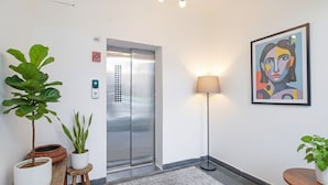 A modern elevator with a digital display, a floor lamp, and a framed abstract painting on the wall. - FabHotel Saket Inn (Bhopal)