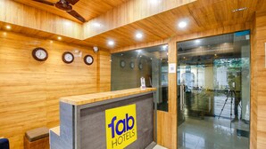 A reception desk with a 'fab hotels' sign, wooden panel walls, and a ceiling fan. - Fabexpress Sunshine Regency (Bhopal)