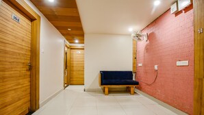 A hallway with a blue bench, wooden doors, and a red brick wall. - Fabexpress Sunshine Regency (Bhopal)