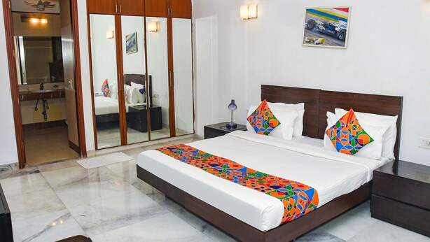 A hotel room with a large bed, a wardrobe, a bathroom, and a wall-mounted picture. - FabHotel Premium- 10min Walk from Millennium City Centre Gurugram Gurgaon (Gurugram)