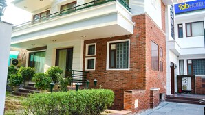 A two-story building with a brick facade, a balcony, and a sign for 'fab HOTEL'. - FabHotel Premium- 10min Walk from Millennium City Centre Gurugram Gurgaon (Gurugram)