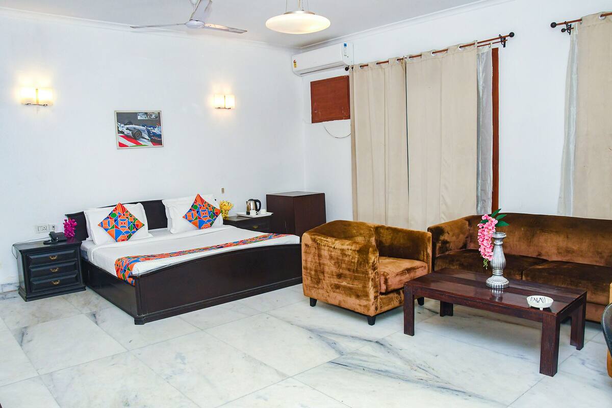 A hotel room with a bed, a brown sofa, a coffee table, and a nightstand.