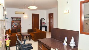 A reception area with a wooden desk, two brown sofas, a bookshelf, and a mirror. - FabHotel Premium- 10min Walk from Millennium City Centre Gurugram Gurgaon (Gurugram)