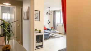 A modern living room with a sofa, coffee table, and a fireplace. There is a hallway leading to another room with a door. - Dans la forêt de Pin by Interhome (Arcachon)