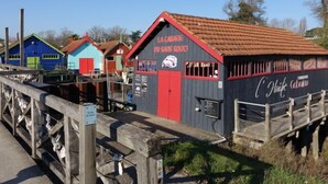 Una hilera de edificios de madera coloridos, con una puerta roja y señalización que indica un restaurante.