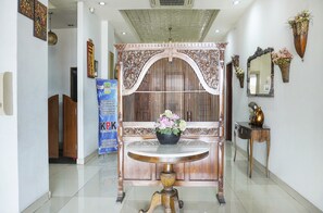 A reception area with a round marble table, a decorative wooden partition, and a blue banner with text. - Collection O Cikarang Near Water Boom Lippo Cikarang Formerly Hotel Teratai (Cikarang)