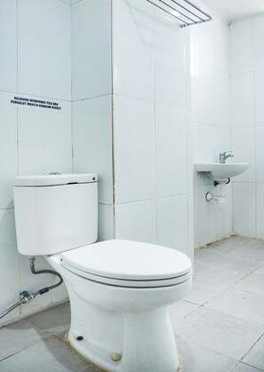 A white toilet with a visible pipe and a wall-mounted sink. - Collection O Cikarang Near Water Boom Lippo Cikarang Formerly Hotel Teratai (Cikarang)