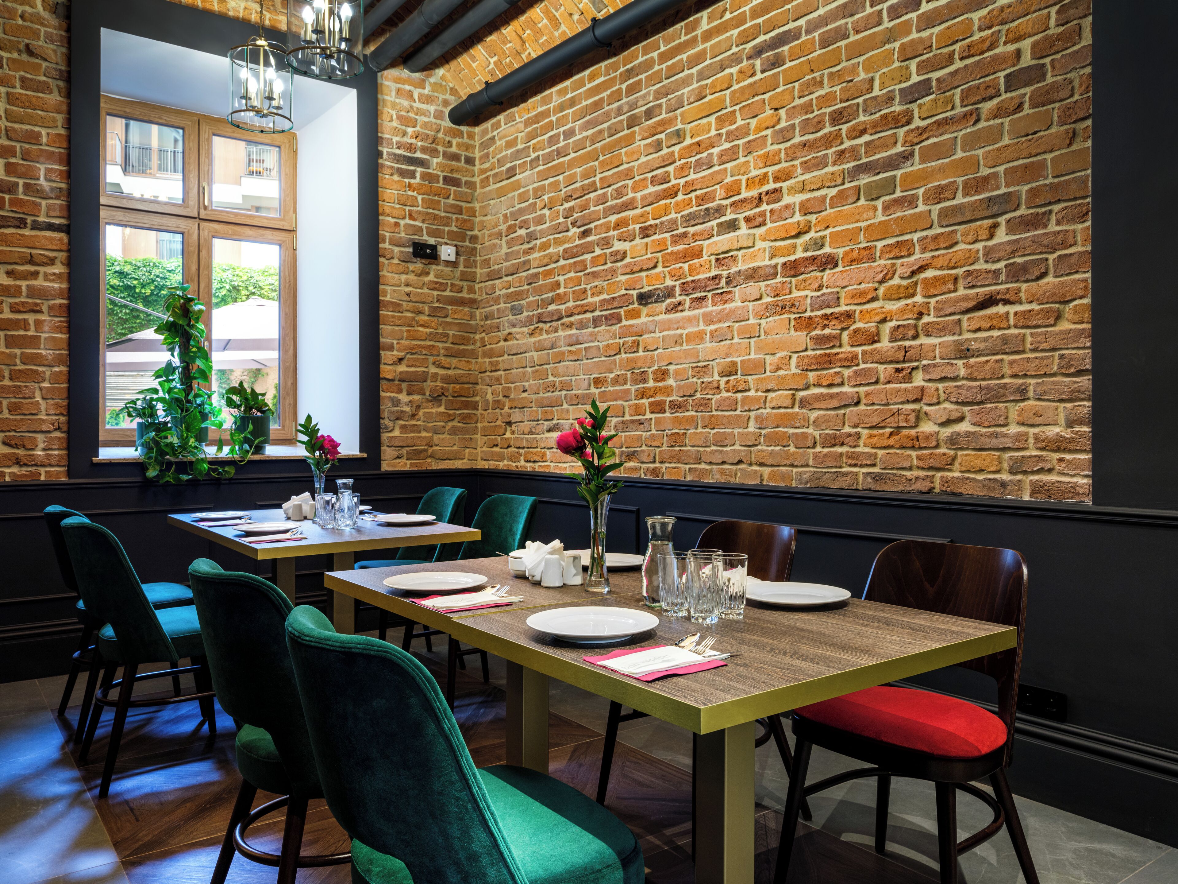Een restaurant met bakstenen muren, houten tafels en groene stoelen.