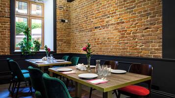 Een restaurant met bakstenen muren, houten tafels en groene stoelen.