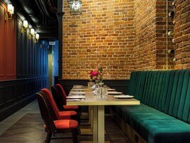 A restaurant with a brick wall, wooden paneling, and a green upholstered bench.