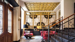 Eine geräumige Lobby mit einer imposanten Treppe, einem bequemen roten Sofa und einer Wand mit geometrischen Mustern.