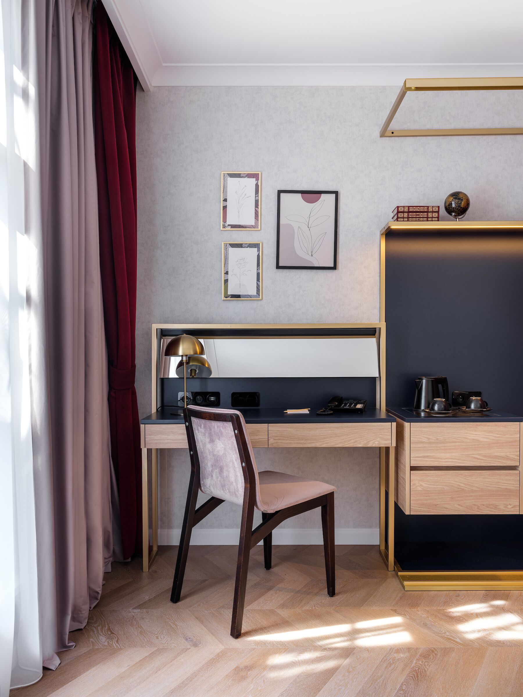 Ein moderner Arbeitsraum mit Schreibtisch, Stuhl und einer Tafel. An der Wand befinden sich zwei gerahmte Kunstwerke, eine Lampe auf dem Schreibtisch und eine Kaffeemaschine.
