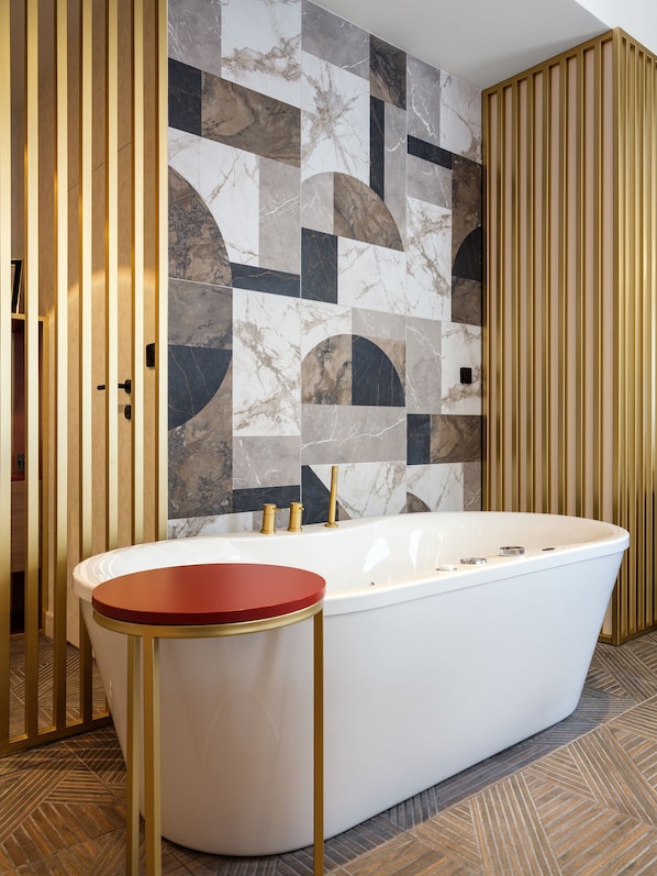 A modern bathroom with a freestanding bathtub, a wooden panel wall, and a herringbone patterned floor.