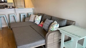 Um espaço de estar compacto com um sofá, uma mesa pequena e um banquinho.