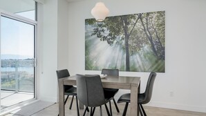 Ein Essbereich mit Tisch und Stühlen, einem großen Fenster und einer Pendelleuchte.
