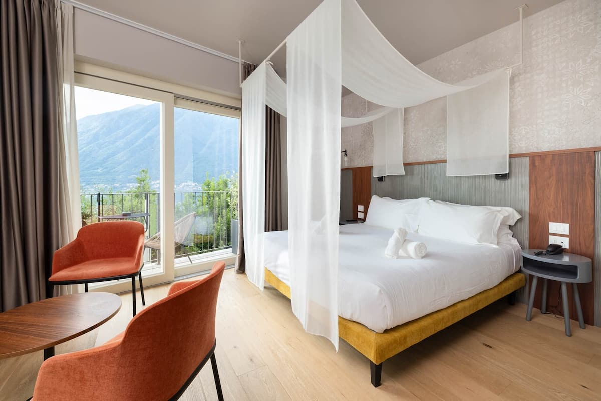 Ein Hotelzimmer mit Bett, Sessel, Tisch und Bergblick.