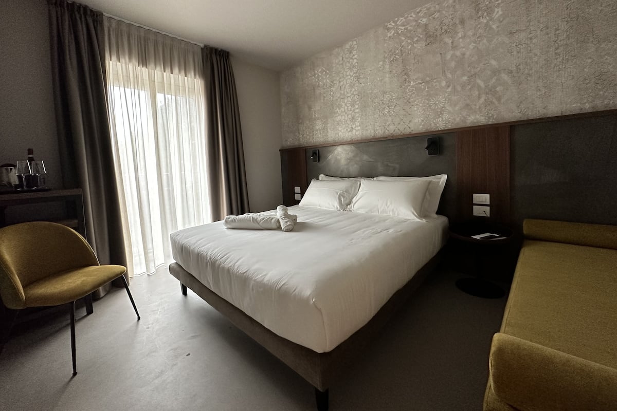 Ein Hotelzimmer mit einem großen Bett, einem Nachttisch, einem Sessel und einem Sofa.