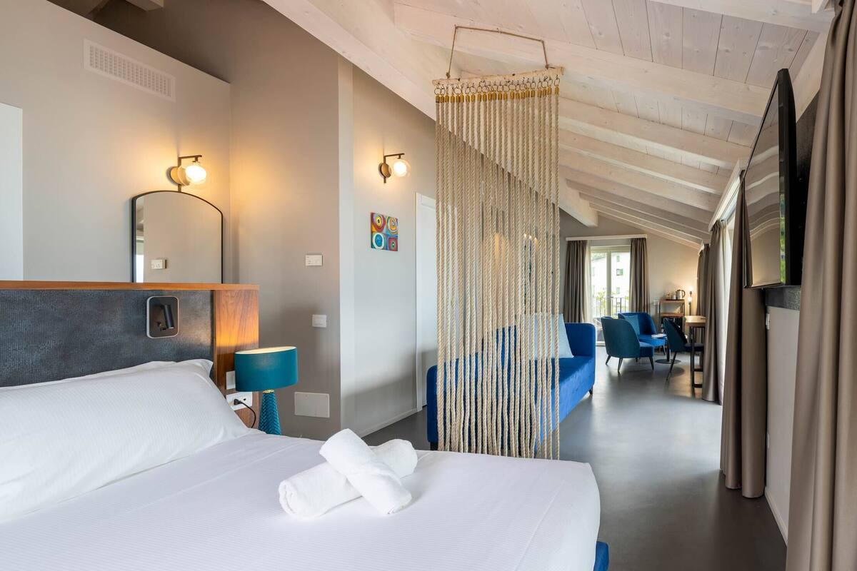 Ein Hotelzimmer mit einem großen Bett, einem Spiegel, einem Schreibtisch und einem Sessel.