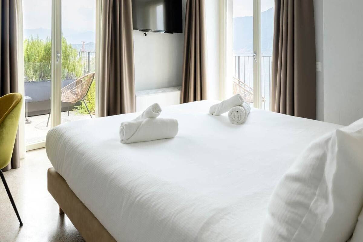 Una habitación de hotel moderna con una cama grande, un televisor de pantalla plana y un balcón con vistas.