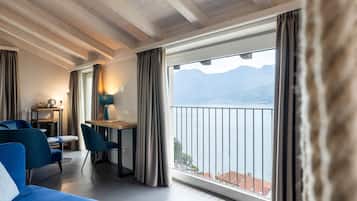 A hotel room with a balcony, a bed, a desk, and a chair.