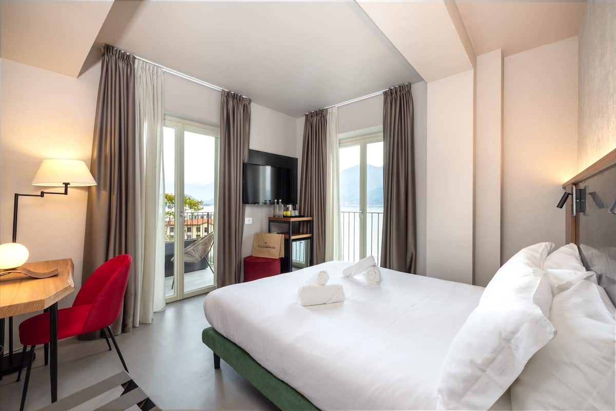 Ein Hotelzimmer mit einem großen Bett, einem Schreibtisch mit Stuhl, einem Fernseher und Blick ins Freie.